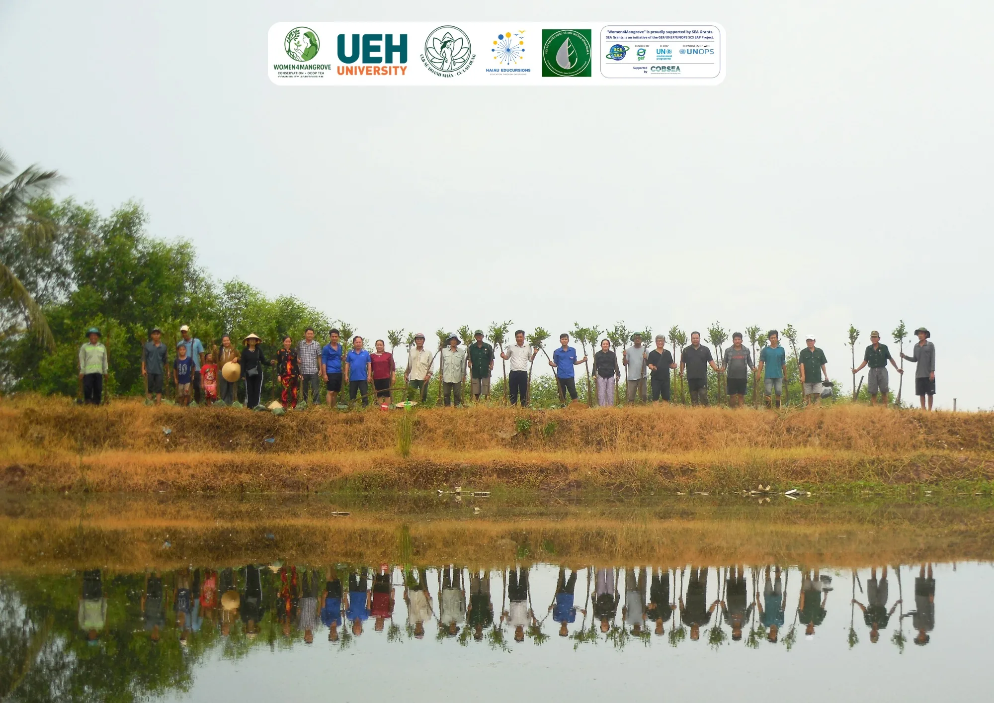 Local residents and the Women4Mangrove team holding mangrove apple seedlings on a dike in Cu Lao Dung, Can Tho